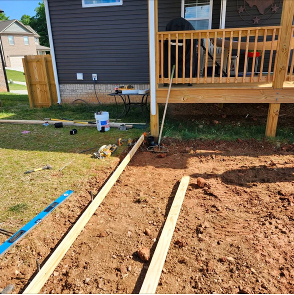 Prepared ground and forms beside a backyard deck